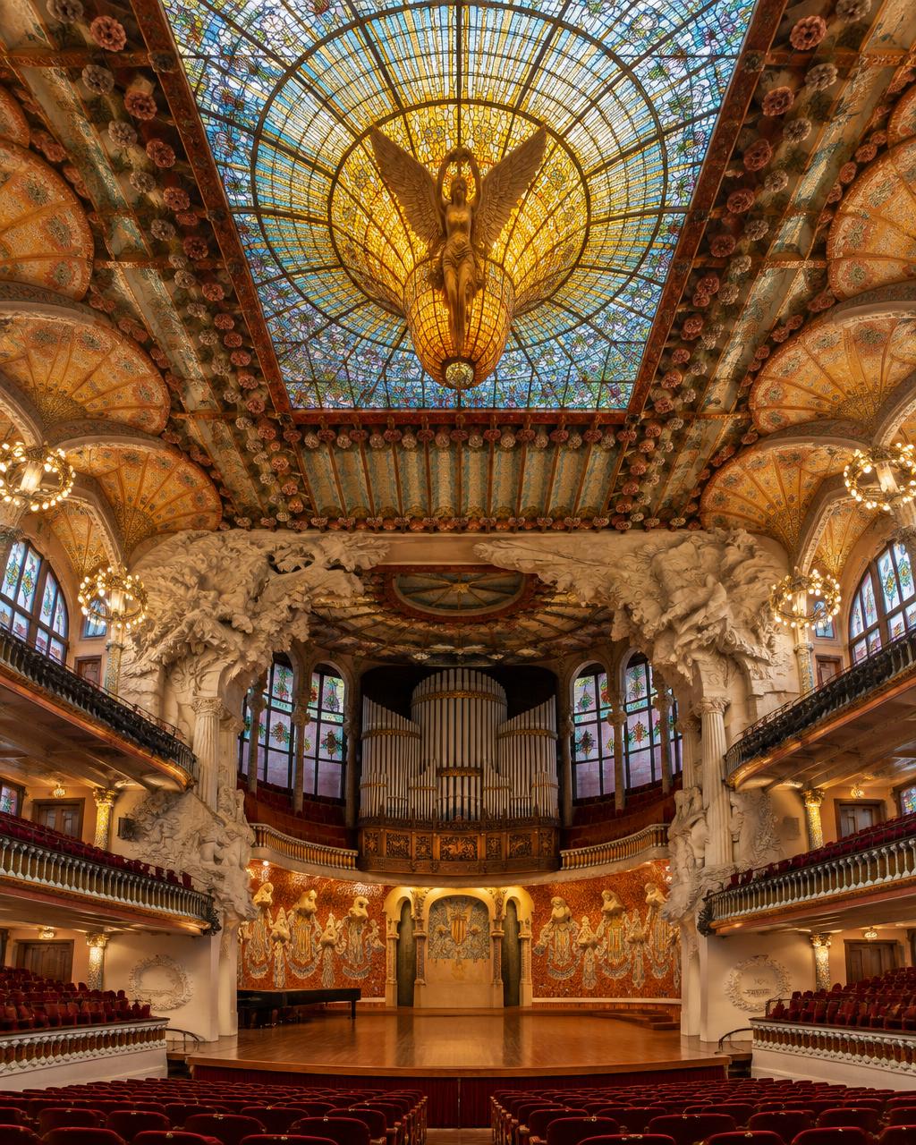 Interior del Palau de la Música Catalana: techo de vidriera y escenario vistos desde las butacas